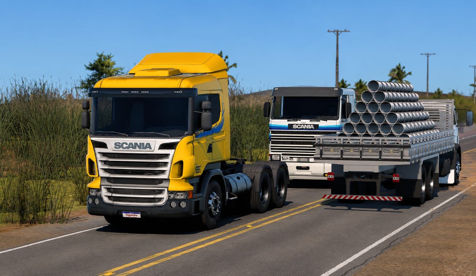 Scania amarelo e Scania 113 branco carregado com tubos na rodovia