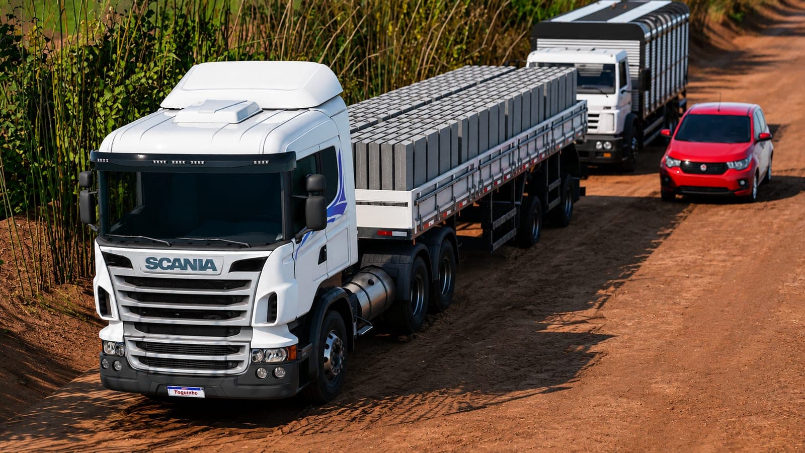 Scania branco carregado com blocos em estrada de terra